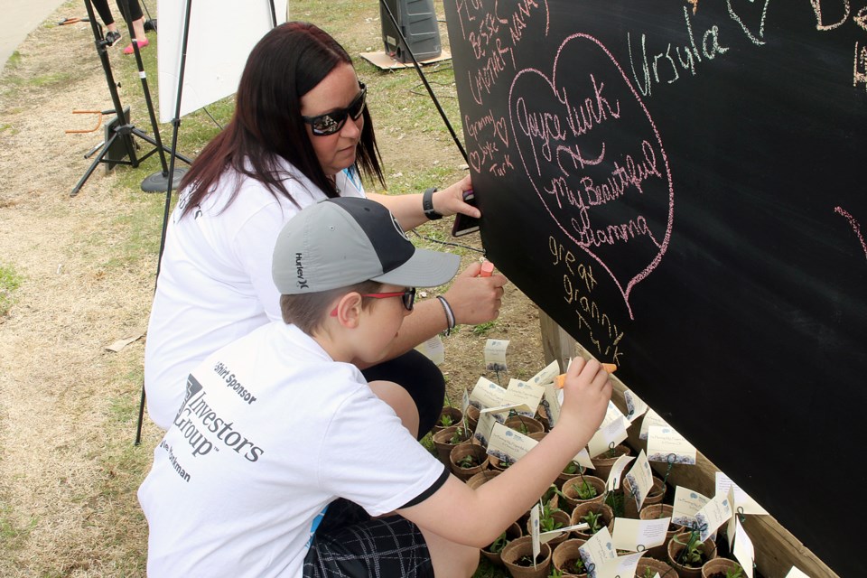 Jen Alton and Etan Fabiano sign a chalkboard in support of Joyce Turk, who was honoured on Saturday, May 26, 2018 at the annual Walk for Alzheimer's. (Leith Dunick, tbnewswatch.com)