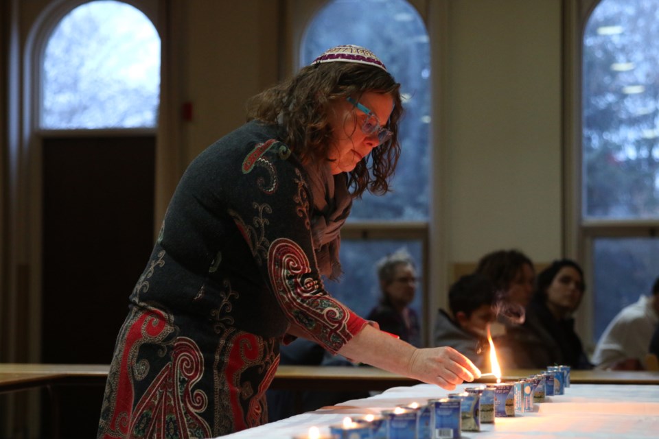 During a local vigil at the Shaarey Shomayim Synagogue, Jenny Roth lights a candle for each of the 11 victims of last week's deadly shooting at the Tree of Life Synagogue in Pittsburgh, as well as two African-Americans killed in Kentucky the same day. (Photos by Doug Diaczuk - Tbnewswatch.com). 