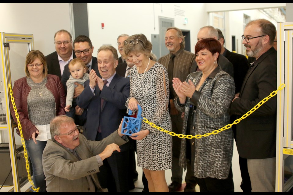 Former Confederation College president Jim Madder and current president Kathleen Lynch unlock a ceremonial digitally printed lock to mark the grand opening of the Thunder Bay School's TEC Hub on Friday, Oct. 19, 2018. (Leith Dunick, tbnewswatch.com)