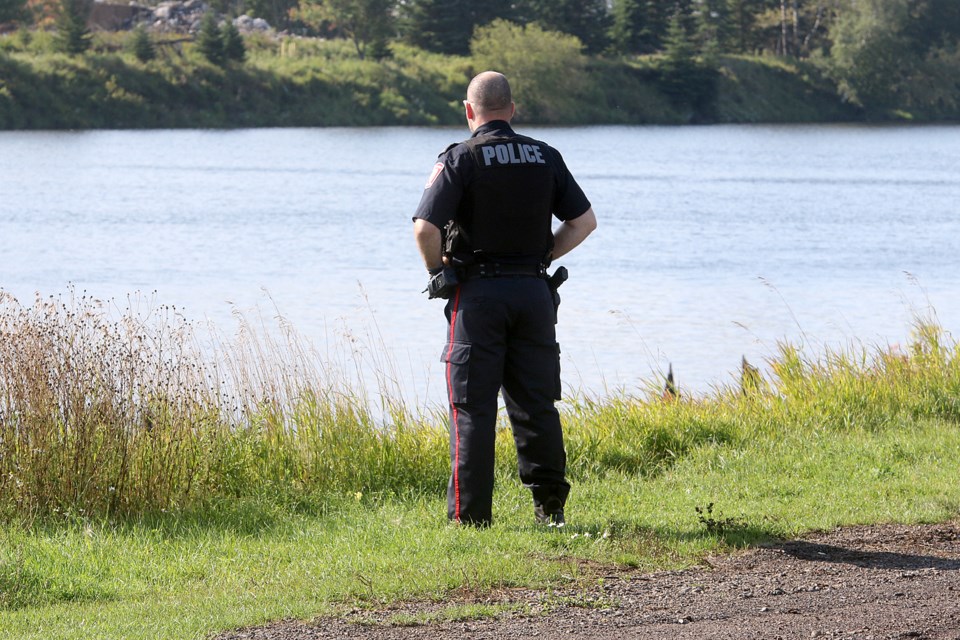 A Thunder Bay Police Service officer stands watch on Saturday, Sept. 1, 2018 alongside the banks of the Kaminisitiquia River, where the body of a man was pulled from the water earlier that day. (Leith Dunick, tbnewswatch.com)