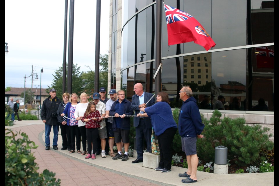 Family members of the founders of the Canadian Merchant Navy Veterans Association of Thunder Bay and city officials hoist the Merchant Navy flag at city hall. (Photos by Doug Diaczuk - Tbnewswatch.com). 