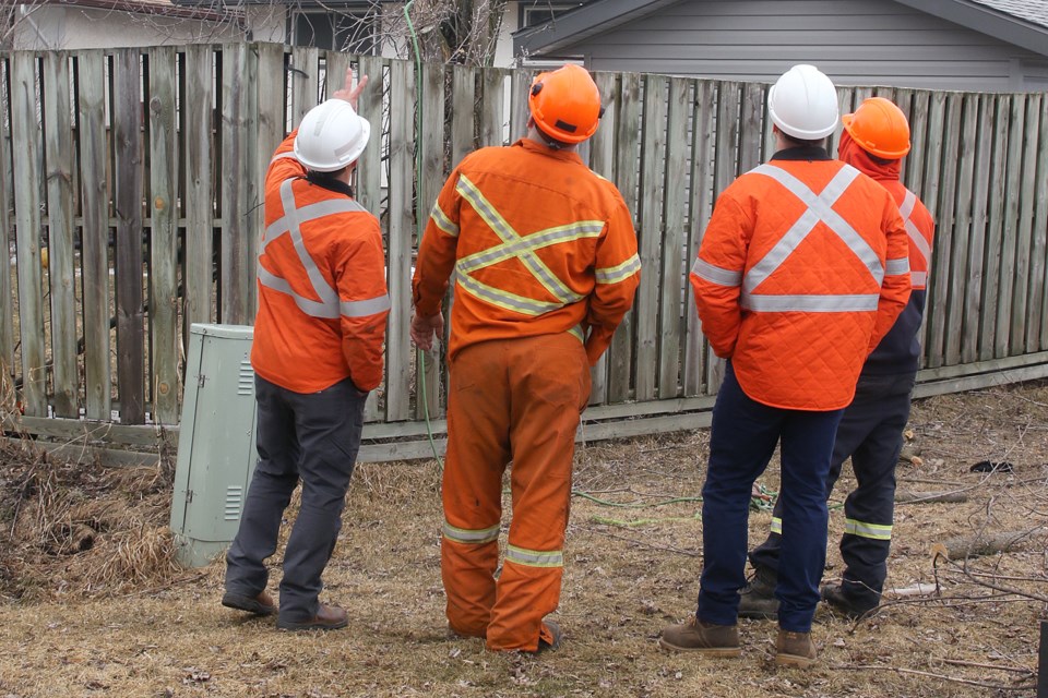 Synergy North workers discuss an electrocution that took place on Kensington Drive on Monday, April 8, 2019. (Leith Dunick, tbnewswatch.com)