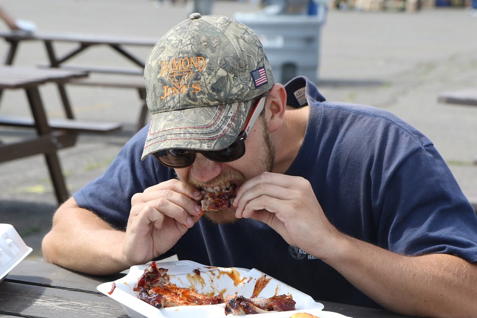 Mitchell Bagdon tests out a rack of ribs on Friday, Aug. 23, 2019 at the Thunder Bay Rib Fest at the Canadian Lakehead Exhibition grounds. (Leith Dunick, tbnewswatch.com)