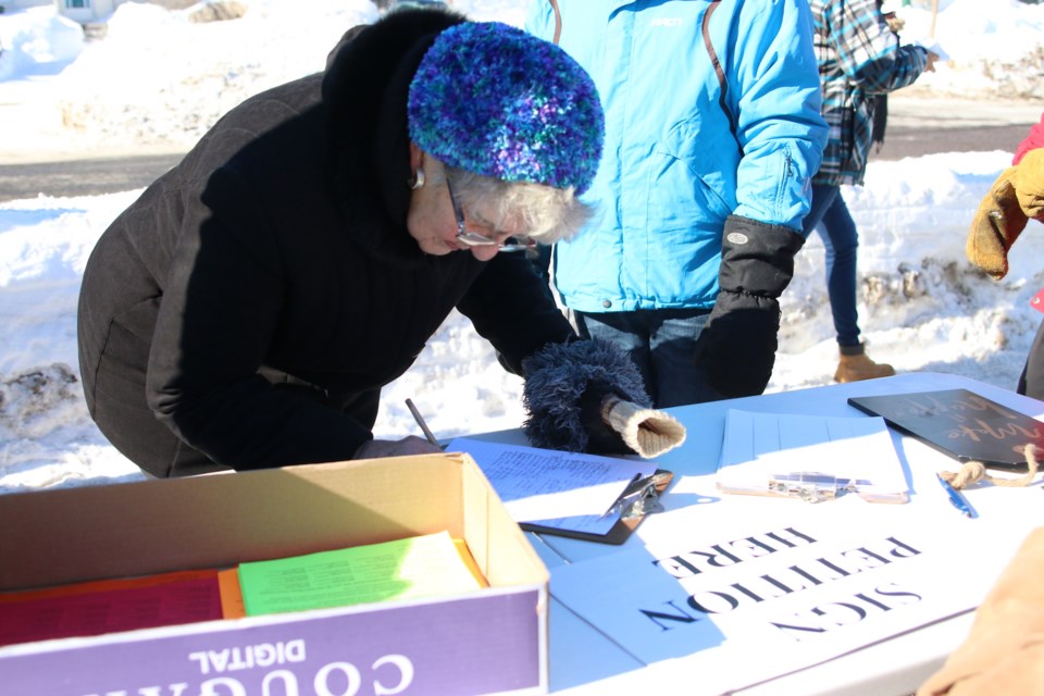 Linda Kennedy, who used to swim at Dease Pool when she was growing up, signs a petition to save the facility durning a rally on Monday. (Photos by Doug Diaczuk - Tbnewswatch.com). 