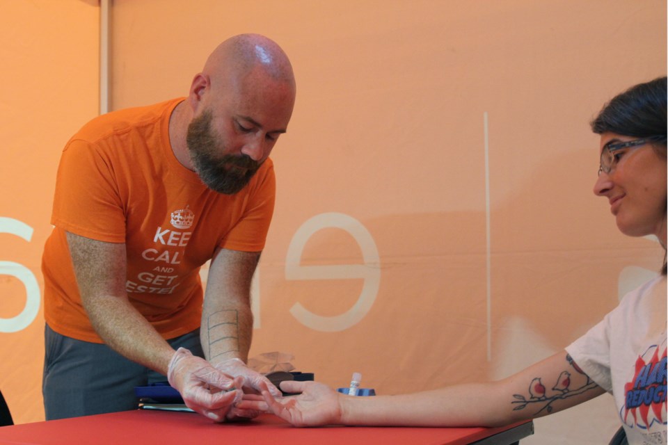 Kyle Lees administering a blood test to Tonya Muchano inside the Elevate NWO tent at Victoriaville mall. (Michael Charlebois, tbnewswatch) 