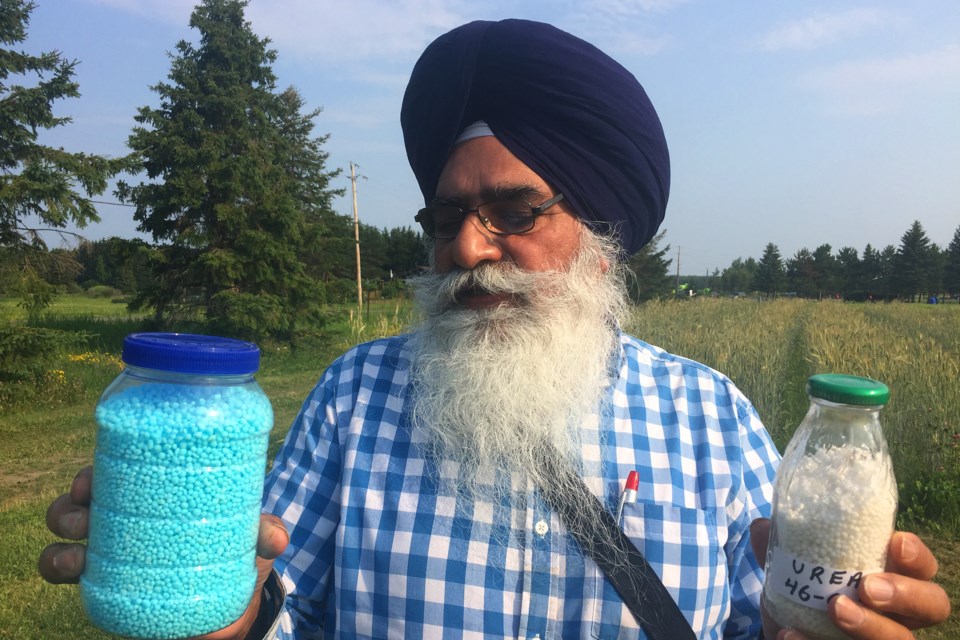 Dr. Tarlok Singh Sahota holding Urea Super Granules (left) at the annual tour at Lakehead's University Agricultural Research Station. (Michael Charlebois, tbnewswatch)