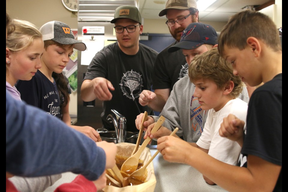 Kids at the Rooted in Nature Adventure Camp at Confederation College had to keep stirring the hot syrup to make it crystallize and turn into maple sugar. (Photos by Doug Diaczuk - Tbnewswatch.com). 