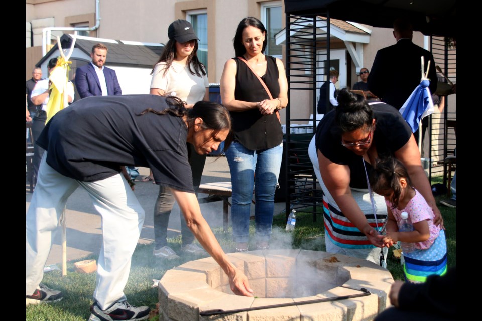 People make offerings of tobacco following the lighting of a sacred fire outside Jenkens Funeral Home. (Photos by Doug Diaczuk - Tbnewswatch.com).  