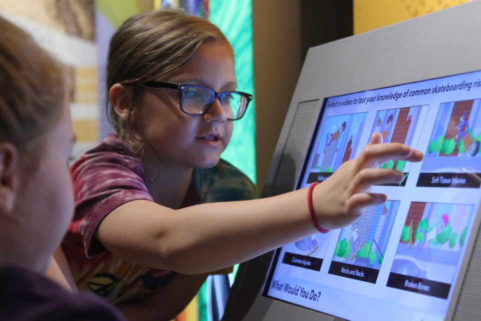 Elizabeth Paradis playing with an interactive display at the Beyond Human Limits display at the Thunder Bay Museum on July 28, 2019. (Michael Charlebois, tbnewswatch)