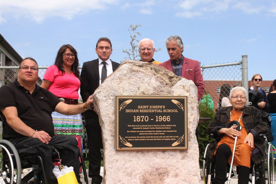 Phillip Pelletier (left), Ann magiskan, Pino Tassone, Deacon Armand Danis, Bill Mauro, and Dolores Wawia in front of the monument. (Michael Charlebois, tbnewswatch)