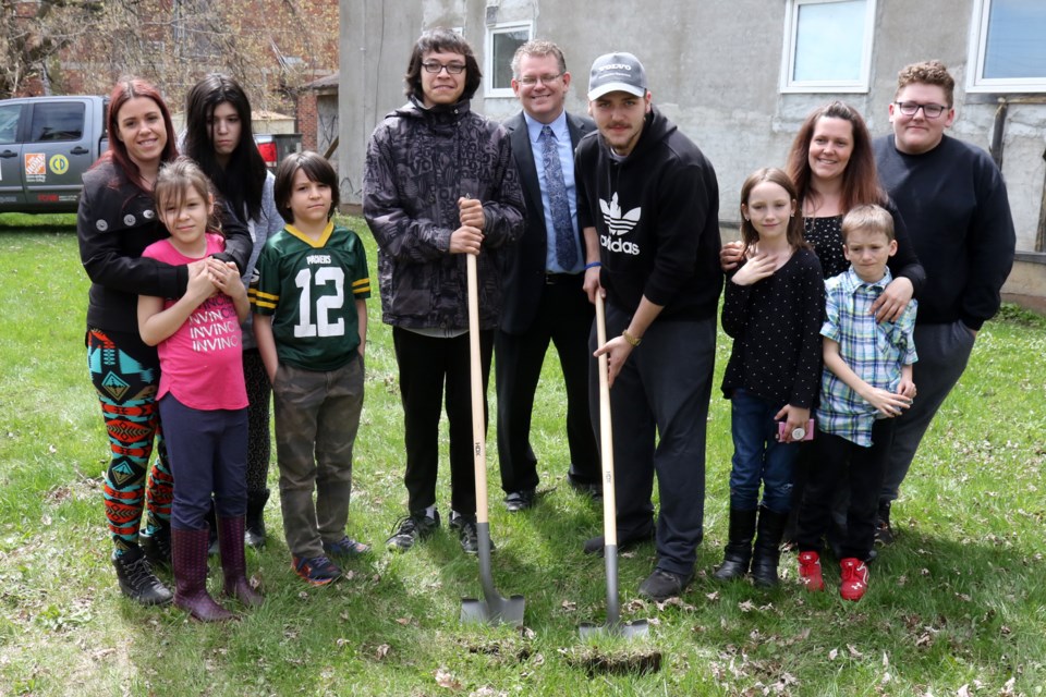 Melissa Keefe (from left), daughters Alexis Laird, 8, Alana Ironstand, 13, and sons Kyle Ironstand, 10 and Kevin Ironstand, 17, were joined by Habitat for Humanity Thunder Bay CEO Ryan Moore and new neighbours Bryce Muratagic, 17, Sierra Woodbeck, 11, Shanda Woodbeck, Zackary Woodbeck, 9, and Brandon Woodbeck, 16, on Thursday, May 16, 2019 at an empty lot on Leith Street where their new home will be built. (Leith Dunick, tbnewswatch.com)