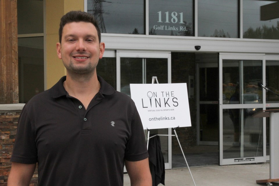 Chris Ferguson, president of On The Links, poses behind the logo on Golf Links Road. (Michael Charlebois, tbnewswatch)