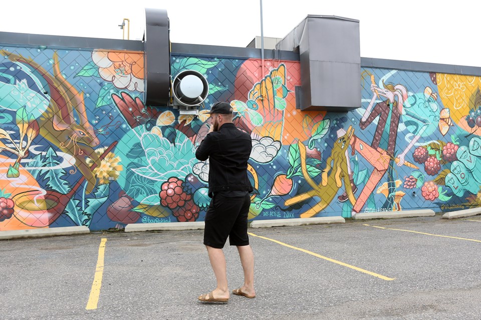 Artist Boy Roland photographs the mural he helped create at Roots to Harvest's Fort William Road building. (Leith Dunick, tbnewswatch.com). 