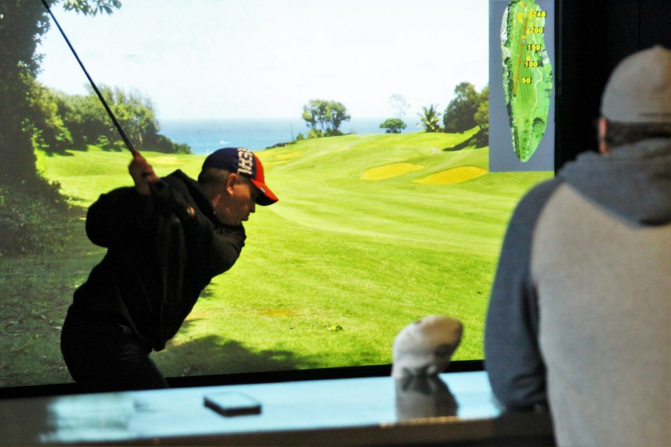 Customers play at an indoor golf simulator at On The Links. (Ian Kaufman, Tbnewswatch)