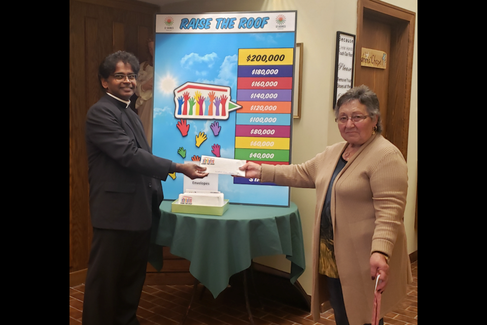 Fr. James Panikulam accepts a donation from St. Agnes parishioner Felicia Urbanski (submitted photo)