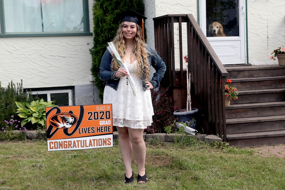 Brenna Prouse's dog Scout watches quietly in the background on Tuesday, June 16, 2020, as she receives her graduation cap and gown from staff at Westgate Collegiate and Vocational Institute. (Leith Dunick, tbnewswatch.com). 