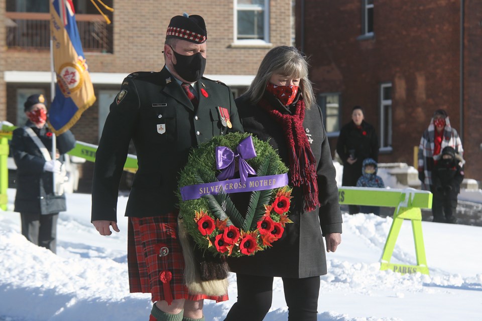 Col. Jim Davis of the Lake Superior Scottish Regiment escorts Silver Cross Mother Carol Klukie, whose son Josh died in 2006 in Afghanistan, to lay a wreath on Wednesday, Nov. 11, 2020 at the Waverly Park cenotaph. (Leith Dunick, tbnewswatch.com)
