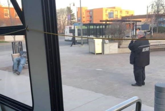 A security guard takes pictures of a two men slumped on a bench at the Thunder Bay city hall transit terminal. (Tatjana Ignace/Facebook)
