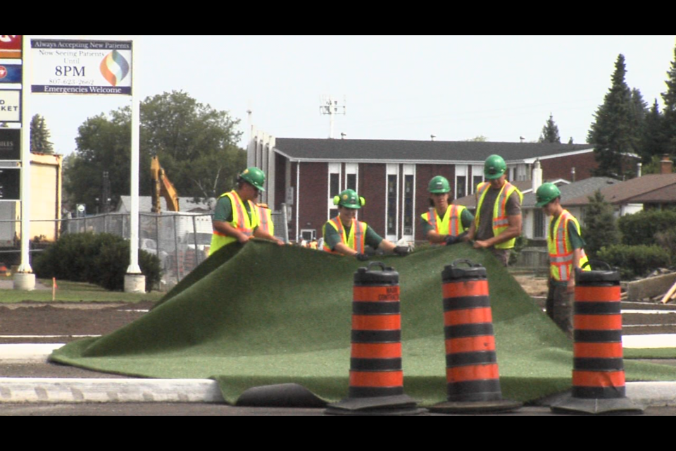 A piece of artificial turf was laid down on Aug. 9, 2021 at the new roundabout under construction at Edward St. and Redwood Ave. (Alex Flood/TBTV photo)