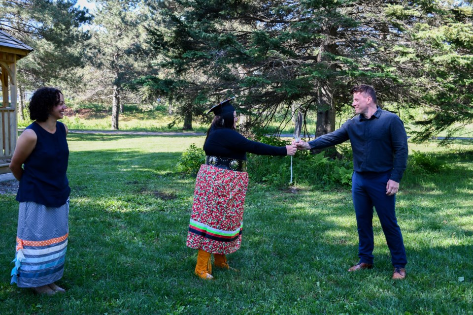 Coordinator Pam Burton watches as alumna Courtney Forbes passes an eagle feather to incomning student Derek Hrynczak to signify the transition to Onajigawin Indigenous Services (submitted photo)