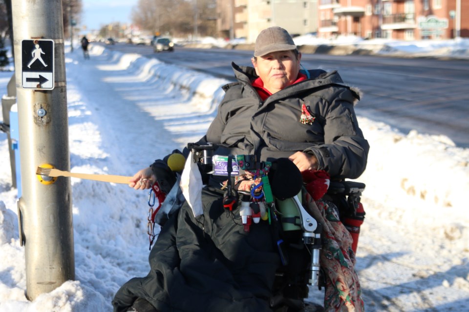 Accessibility advocate, Tracy Hurlbert, demonstrates she sometimes has to use a pole or stick to activate the pedestrian crossing button at the corner of Arthur Street and Selkirk Street. (Photos by Doug Diaczuk - Tbnewswatch.com). 
