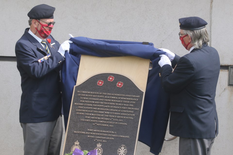 Co-chairs of the 100th anniversary ceremony of the adoption of the poppy, Del Babcock (left) and Robert Cutbush, unveil a plaque which will hang iniside Thunder Bay's Prince Arthur Hotel. (Leith Dunick, tbnewswatch.com)