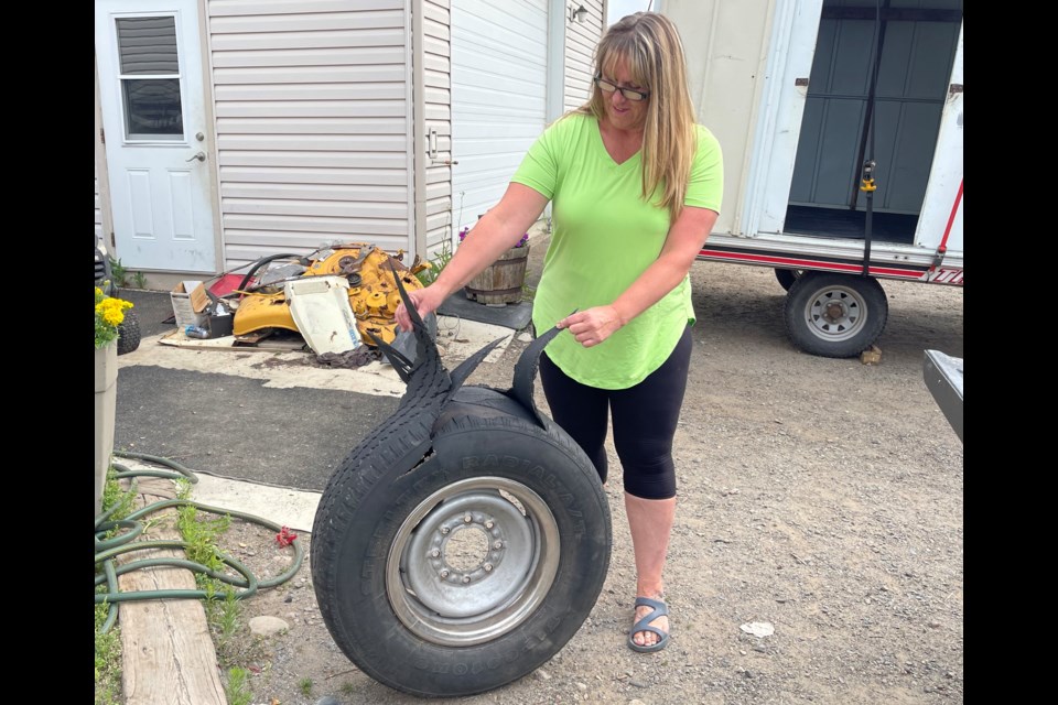 Kim Mozell shows the spare tire that exploded inside the rear of a Suburban on July 4, 2021 (Brianne Foley/TBTV photo)