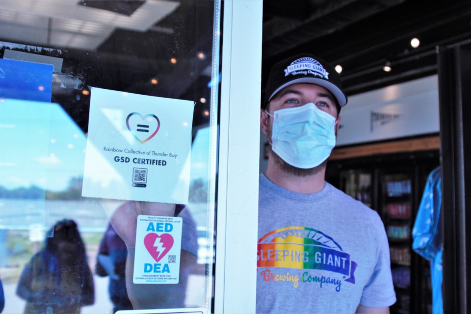 Sleeping Giant Brewing Co. general manager Kevin Brewer affixes the business's newly earned gender and sexual diversity certification. (Ian Kaufman, TBNewswatch)