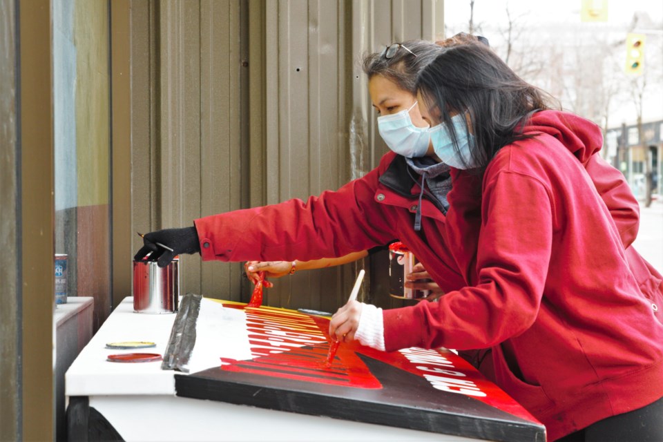 Volunteers paint a donation box at the new Underground Gym location on Friday. (Photos by Ian Kaufman, TBNewswatch)