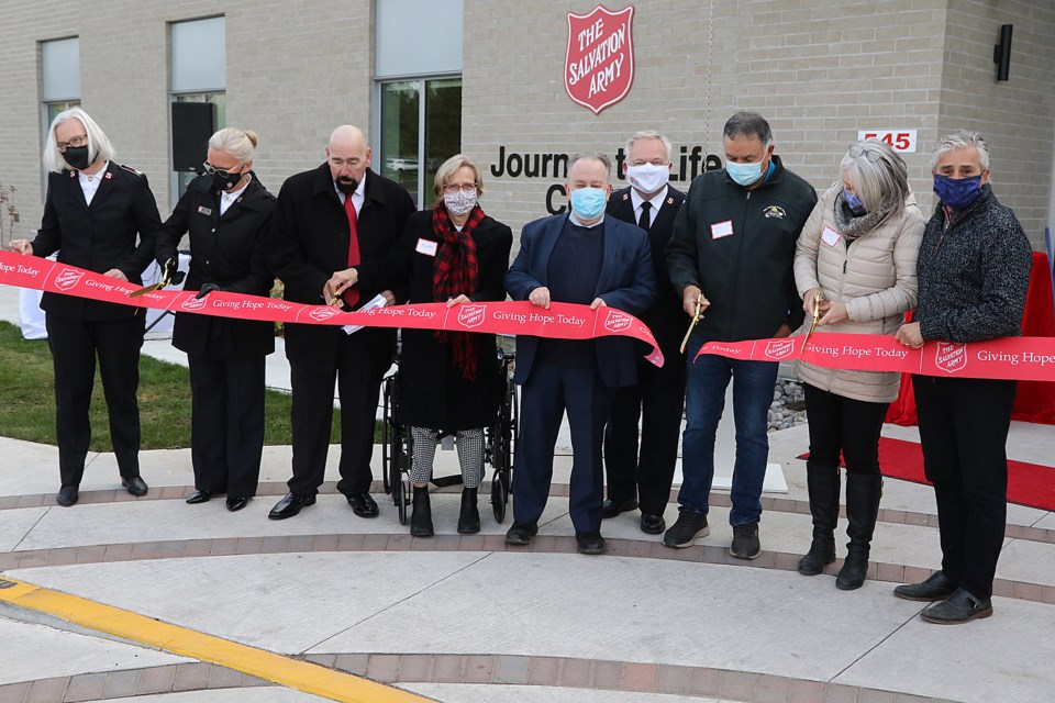 Dignitaries cut a ribbon on Oct. 22, 2021 outside the Salvation Army's Journey to Life Centre in Thunder Bay. From left: Lieut.-Col. Brenda Critch, Major Lori Mitchell, Gary Ferguson, Janet Sillman, Michael Gravelle, Lieut-Col. Shawn Critch, Chief Peter Colins, MP Patty Hajdu and Mayor Bill Mauro. (Leith Dunick, tbnewswatch.com)