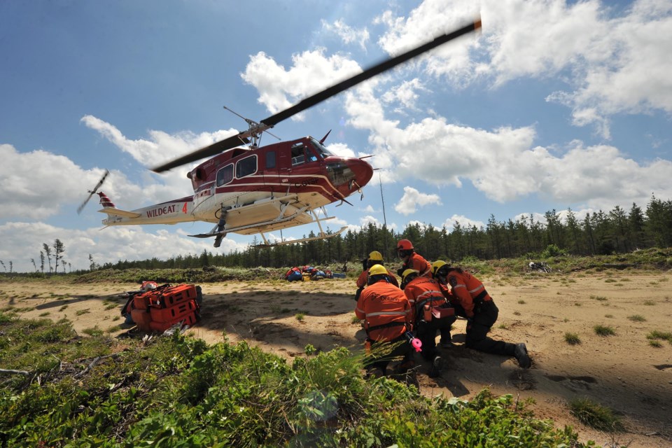 The Adam Jedrasik crew of Ontario fire rangers crouches while a helicopter departs after unloading the crew and equipment during a training exercise north of Dryden (Chris Marchand/AFFES photo)