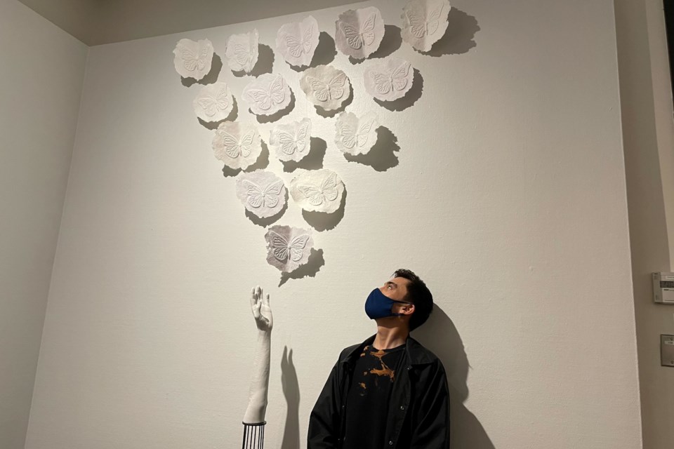 Nathan Cross, a fourth-year graduating student stands in front of one of his works displayed at the Art Gallery