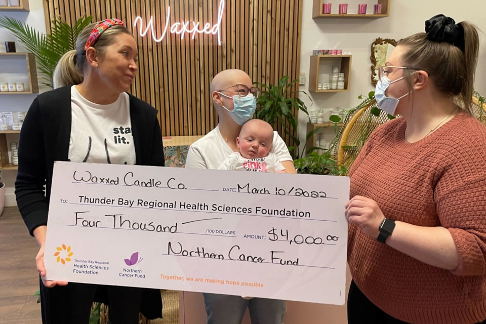 Kate Strange (left), Kailey Elvish (middle left), and Griffin (middle right) pass a $4,000 cheque to Katelyn Fletcher (right)