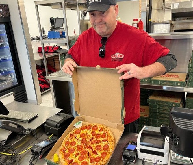 Bryan McGauley showing off a pepperoni pizza during the launch of the Blanket For The Bay initiative at Papa Johns on Waterloo Street North on Monday, December 4, 2023