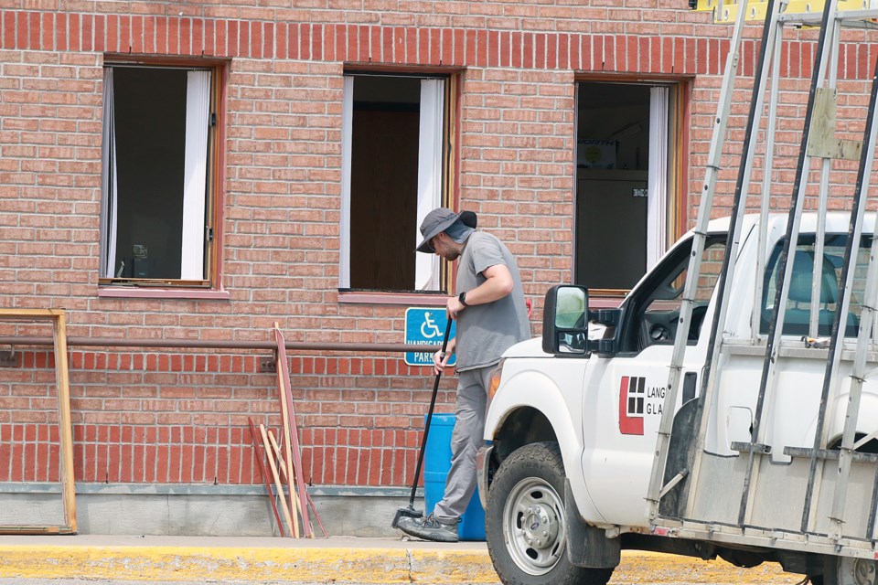 A worker cleans up broken glass on Friday, July 7, 2023 the Thunder Bay 55 Plus Centre, where vandals struck overnight on July 6 and July 7. (Leith Dunick, tbnewswatch.com)