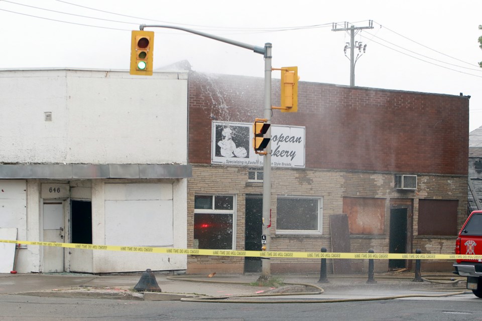 Water pours from the roof of the former European Bakery on Simpson Street after a fire broke out in the building on Sunday, July 9, 2023. (Leith Dunick, tbnewswatch.com)