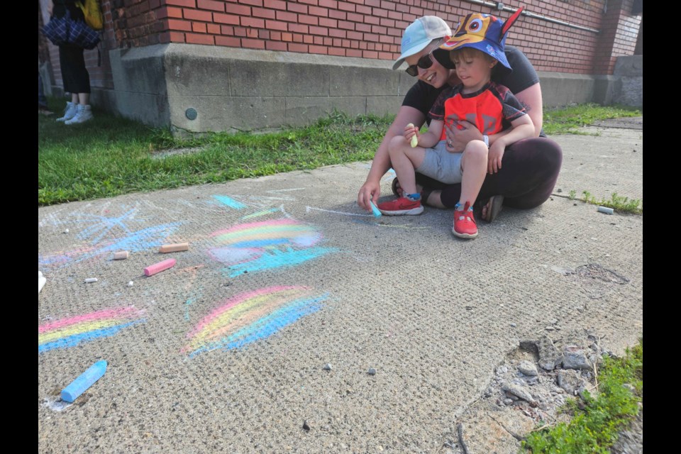 Mother and son enjoy drawing with chalk at the Our Kids Count 25th Anniversary BBQ