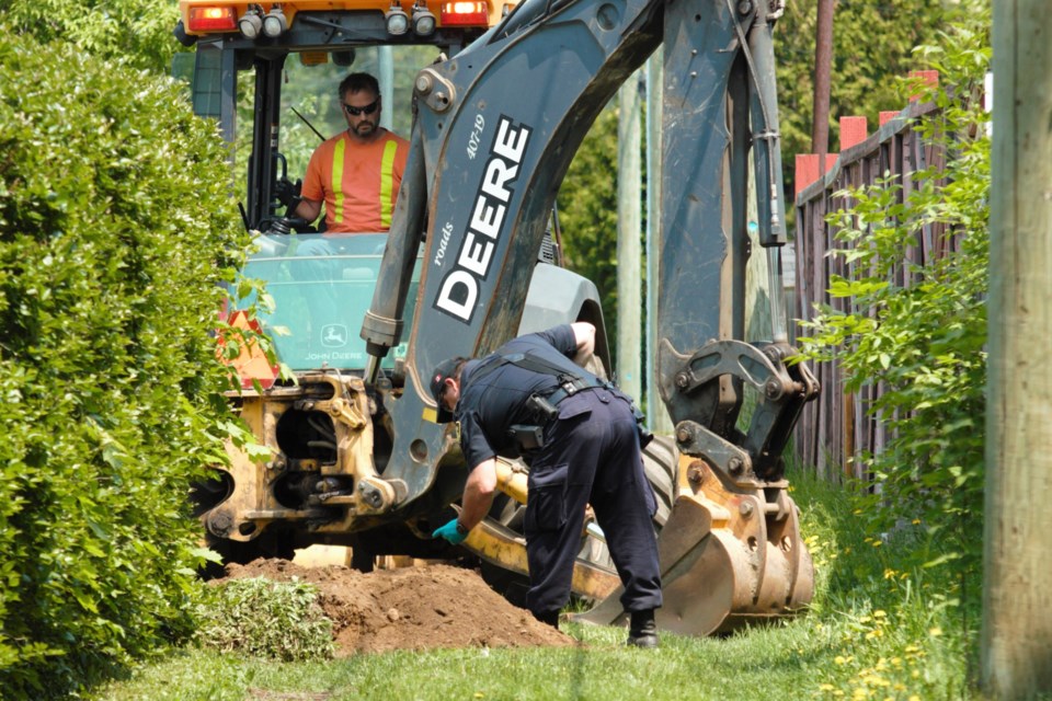 An OPP officer looks through soil unearthed from the backyard of a home on Marlborough Street.