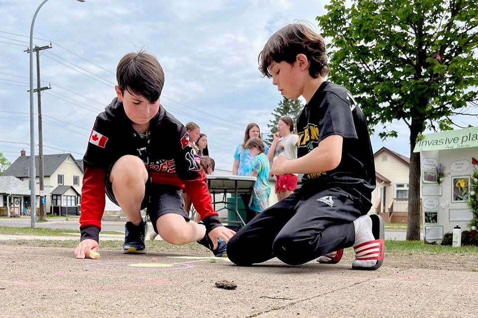 St. Martin School students Nathaniel Venn, 11 (left), and Grady Ladouceur, 10 make environmentally inspired chalk drawings on Friday, June 9, 2023 outside Pope John Paul II School. (Leith Dunick, tbnewswatch.com)