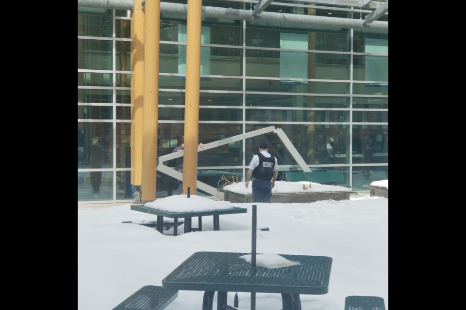 Hospital staff examine a 9-metre length of U-shaped metal that broke loose from the facade and crashed into a courtyard at Thunder Bay Regional Health Sciences Centre on  March 28, 2023 (submitted photo) 