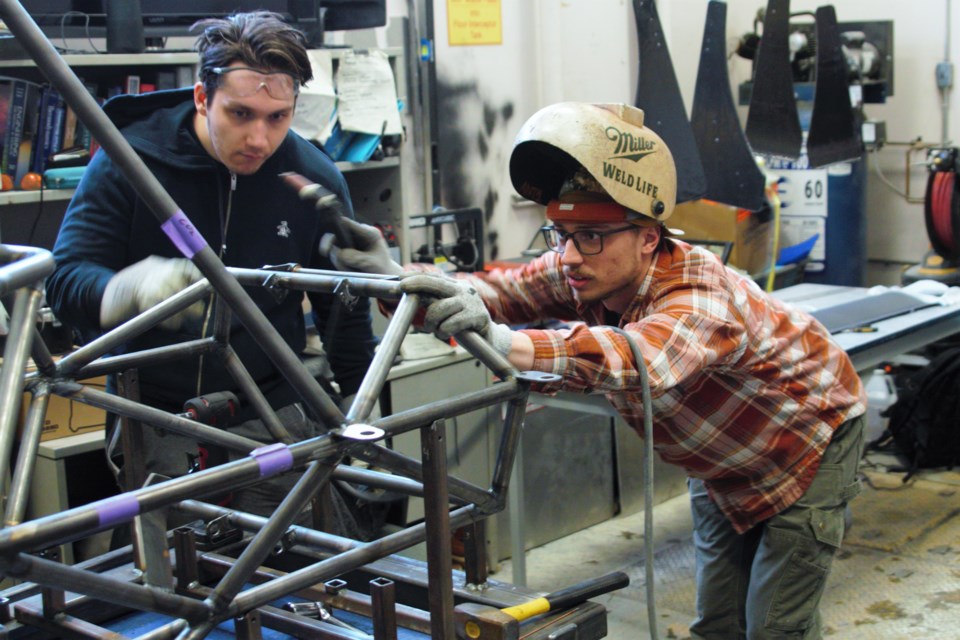 Lakehead FSAE team members Aleksa Grahovac (left) and Antoine Leduc examine the car's anti-roll bar system, which helps increase stability on corners. (Ian Kaufman, TBnewswatch)