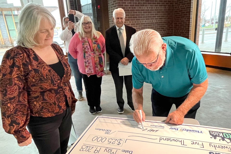 Donor Cliff Friesen (left) signs a $25,000 cheque to PRO Kids' Power to Play Program, watched by program executive director Laura Daniele, on Friday, May 19, 2023 at the Baggage Arts Building at Prince Arthur's Landing. (Leith Dunick, tbnewswatch.com)