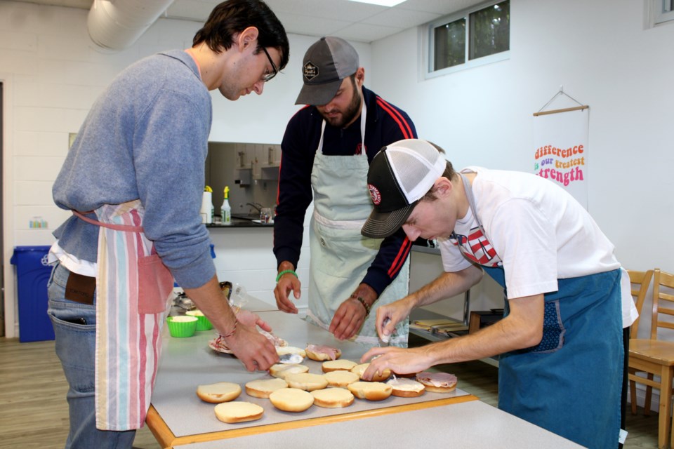 Carter Campbell, left, helps his brother Justin and Jimmy Ulakovic make sandwiches for the Dew Drop Inn at the Rowan Tree Collective on Wednesday afternoon. 