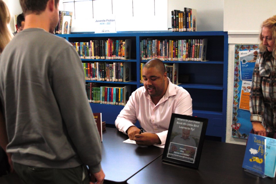 Local author Zachry Hendricken signs a copy of one of his books during a launch event at the Brodie Library on Wednesday.