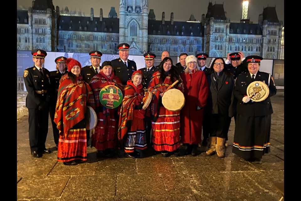 Members of the Thunder Bay Police Service, elders, drummers, Tree of Hope project creator Sharlene Bourdeau and minister of Indigenous services Patty Hajdu pose on Parliament  Hill on Monday evening. 