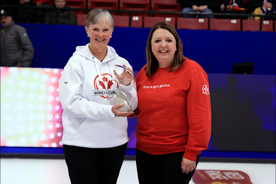 Curling Canada’s officer of Sport Safety and Education, Jennifer Ferris, on the right presents the Joan Mead Builder’s Award for the Scotties Tournament of Hearts to Andrea Ronnebeck.