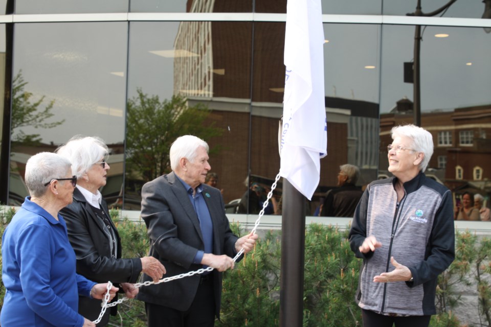 Ken Boshcoff and community members raising the Age Friendly Thunder Bay flag.