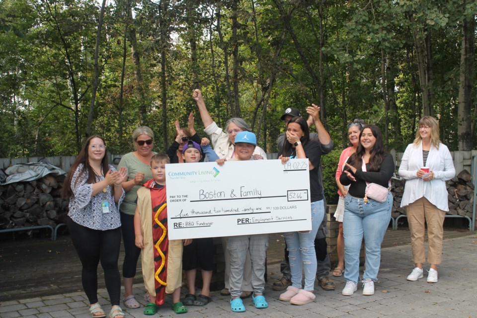 The team from Community Living Thunder Bay and Boston's family celebrate after receiving the cheque.