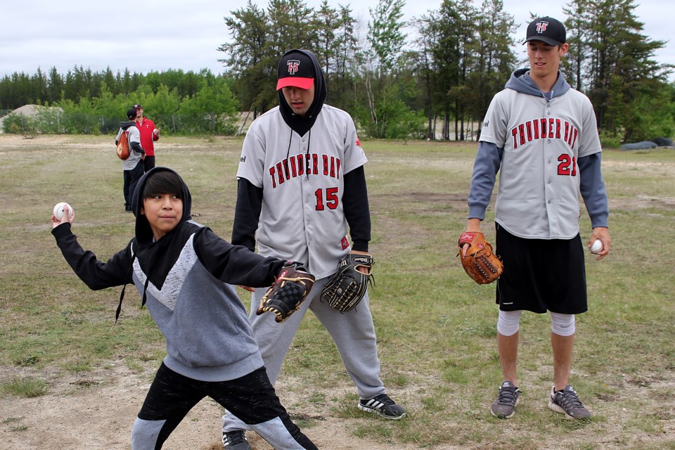 North Caribou Lake First Nation's McCartney Beaver, 11, gets baseball instruction on Saturday, June 24, 2017 from Border Cats J.F. Garon (centre) and Brandon Williamson (Leith Dunick, tbnewswatch.com).