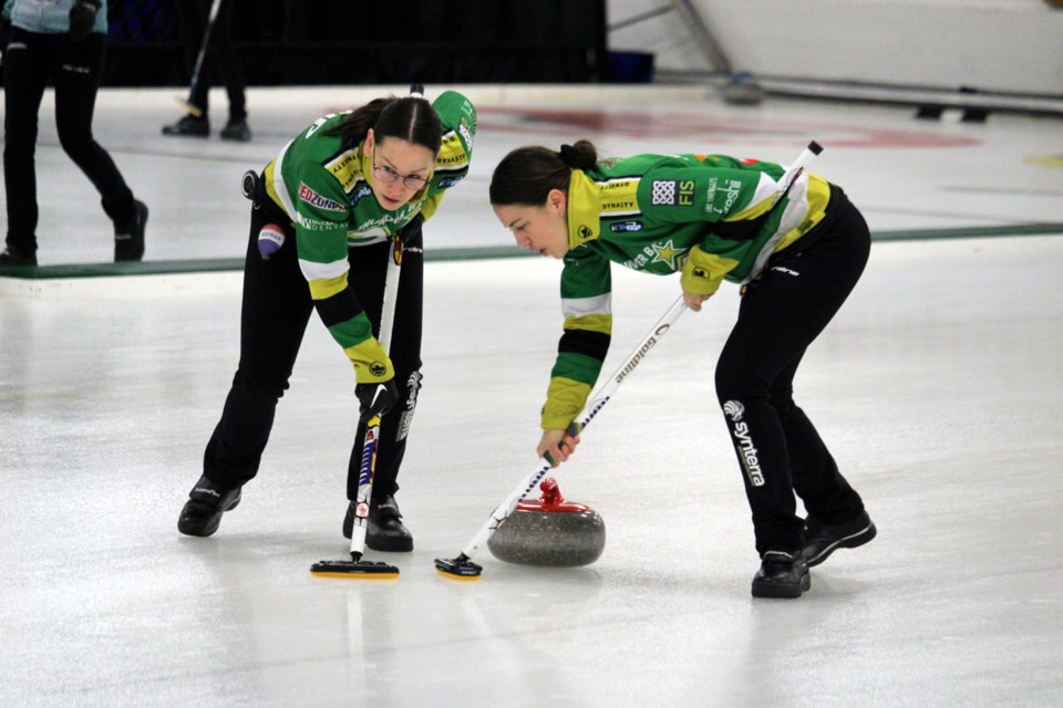 Kendra Lilly, left, and Sarah Potts sweep a stone thrown by skip Krista McCarville.